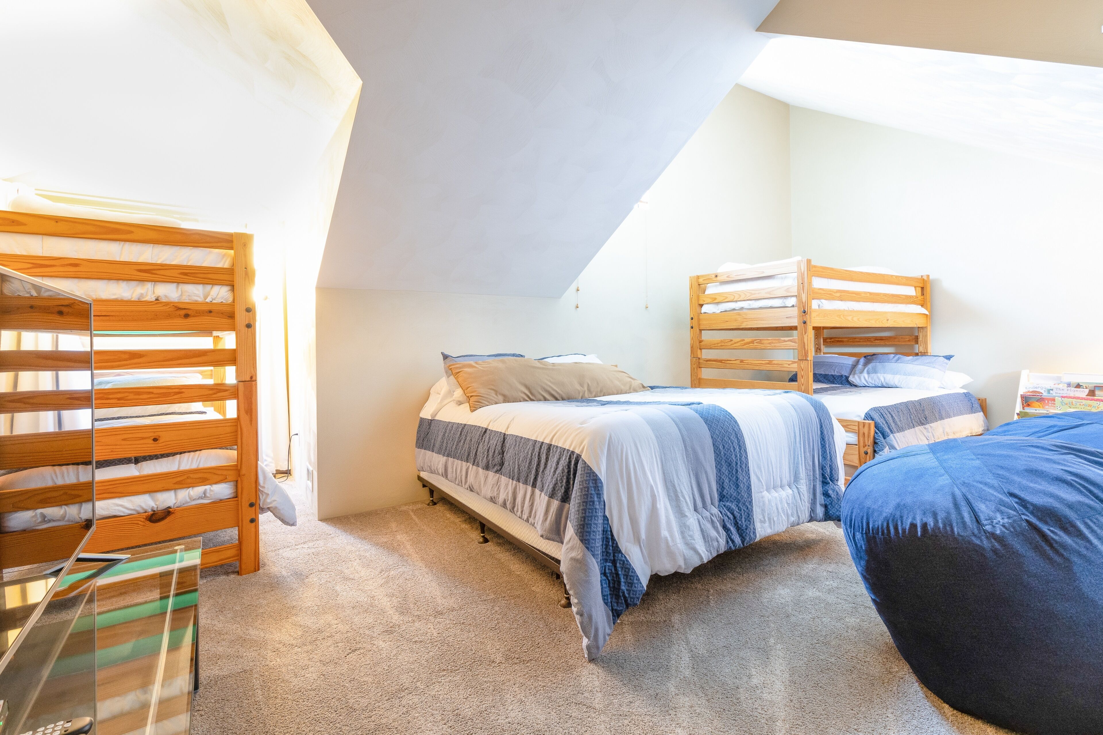 A dormitory room with bunk beds, a desk, and a bookshelf.