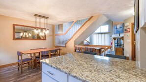 A modern kitchen with granite countertops, wooden dining table, and built-in appliances. - Seven Springs 2BR Loft Premium Condo, sleeps 11! by RedAwning (Champion)