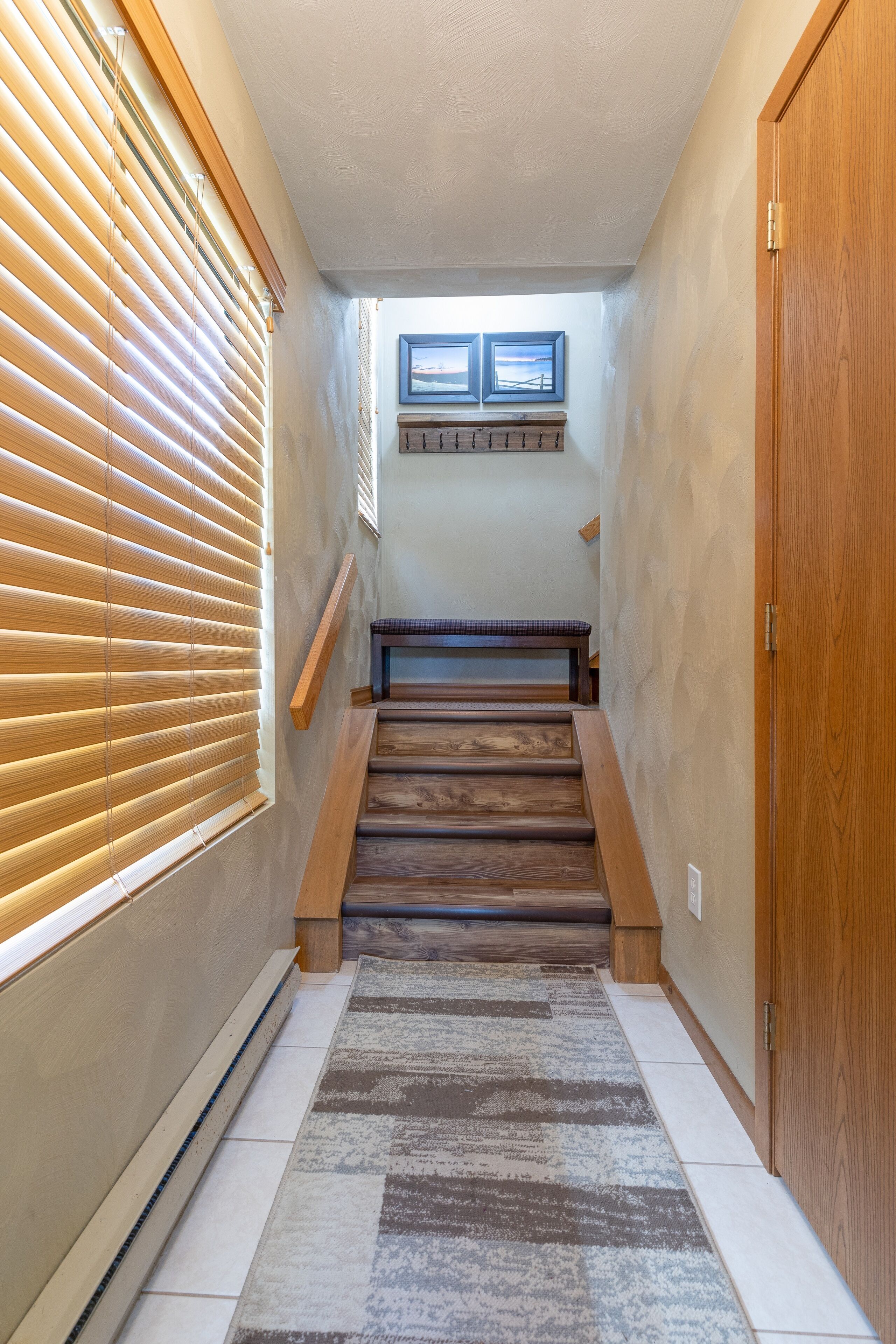 A staircase with wooden steps, a bench, and a small window with pictures.