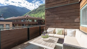 A balcony with a wooden floor, a sofa with cushions, and a potted plant. - Ice House 317 2 Bedroom Condo by RedAwning (Telluride)