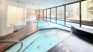 A swimming pool with clear water, a lifeguard chair, and a view of trees outside. - Ice House 317 2 Bedroom Condo by RedAwning (Telluride)