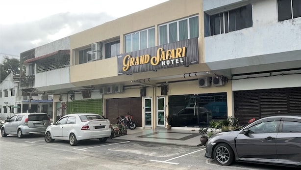 Fachada del Hotel Grand Safari con un área de estacionamiento al frente.