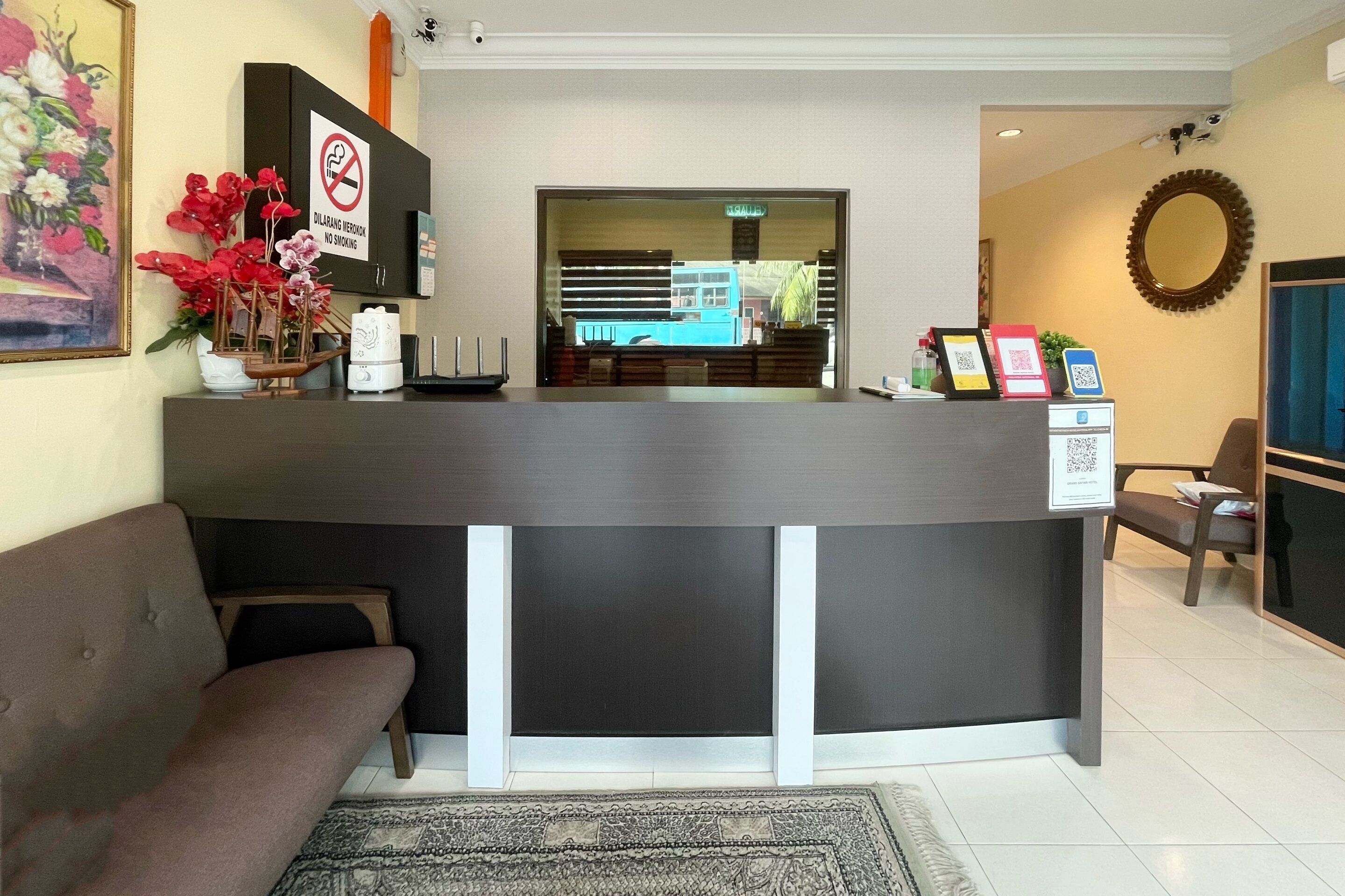 A reception desk with a no-smoking sign, a framed photo, a QR code, and a small plant.