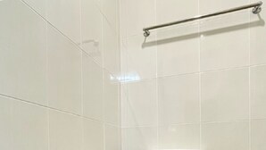 Un inodoro blanco en un baño con paredes y suelo de baldosas blancas.