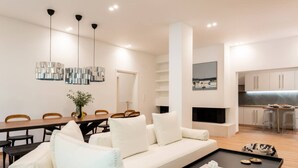 Un salon moderne avec un canapé blanc, une table basse et des luminaires suspendus.