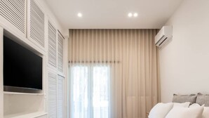 Une chambre moderne avec un grand lit, une télévision et une armoire.