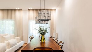 Un espace repas moderne avec une table en bois, des chaises noires et un vase agrémenté de plantes vertes.