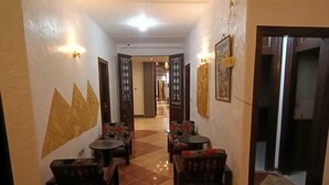 A hallway with a checkered floor, wooden furniture, and wall-mounted light fixtures. - Family Palace Downtown Cairo  (Cairo)