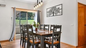 Un espace repas comprenant une table, des chaises, une plante et un luminaire fixé au mur.