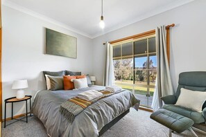A bedroom with a bed, bedside tables, a chair, a window with curtains, and a painting on the wall. - Highfields - Valley Views - Bathurst Acreage (Robin Hill)
