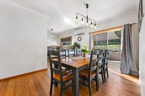 A dining area with a wooden table and chairs, a hanging light fixture, and a view of the outdoors. - Highfields - Valley Views - Bathurst Acreage (Robin Hill)