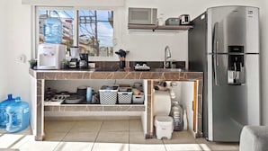 Una cucina compatta con frigorifero, microonde e dispenser per l'acqua.
