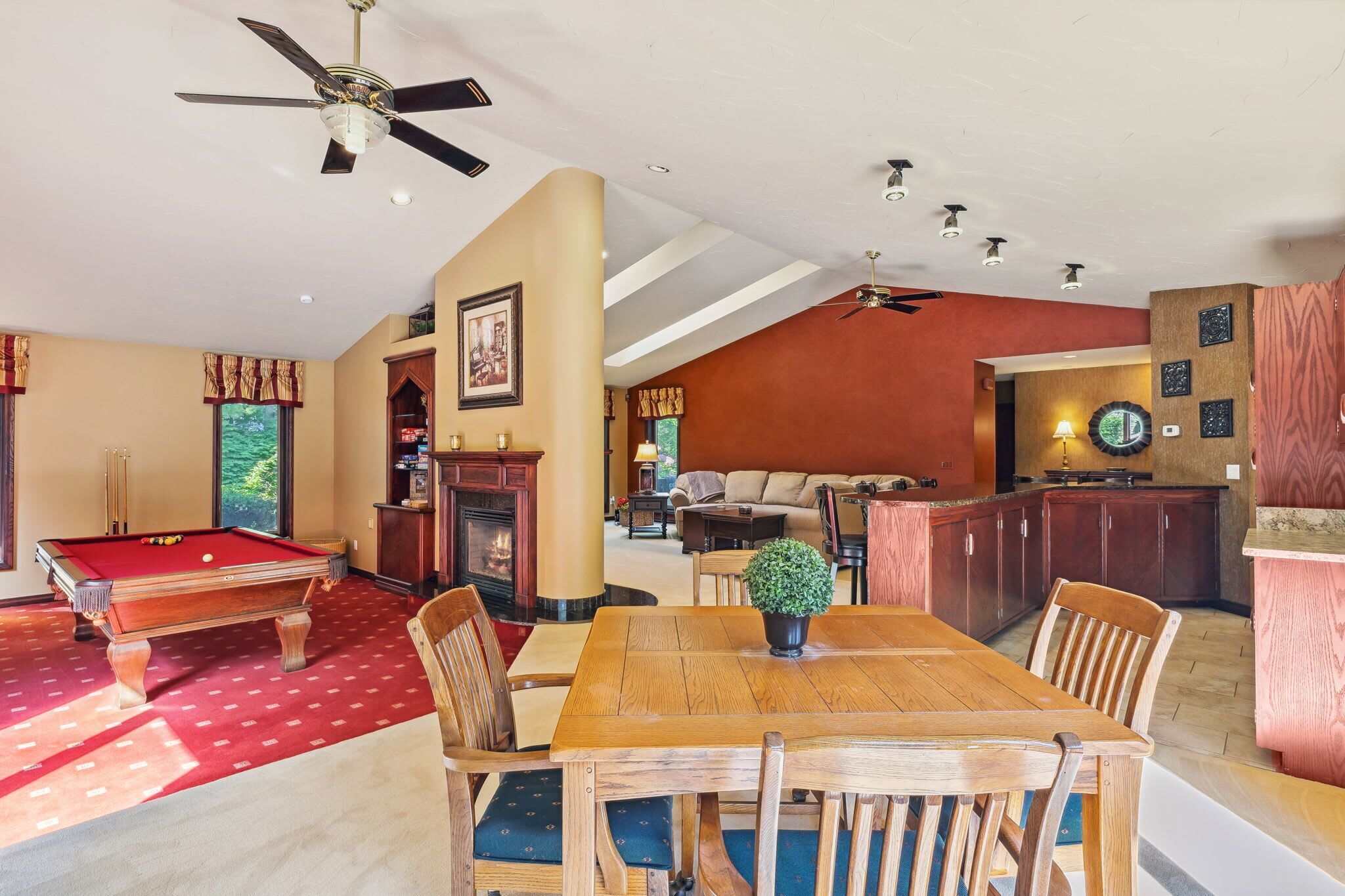 A spacious living room with a pool table, a dining area, and a kitchen.