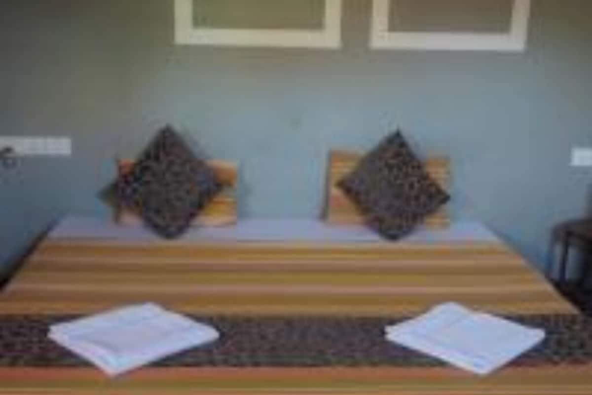 A bed with striped bedding, two pillows, and a folded towel on the bed.