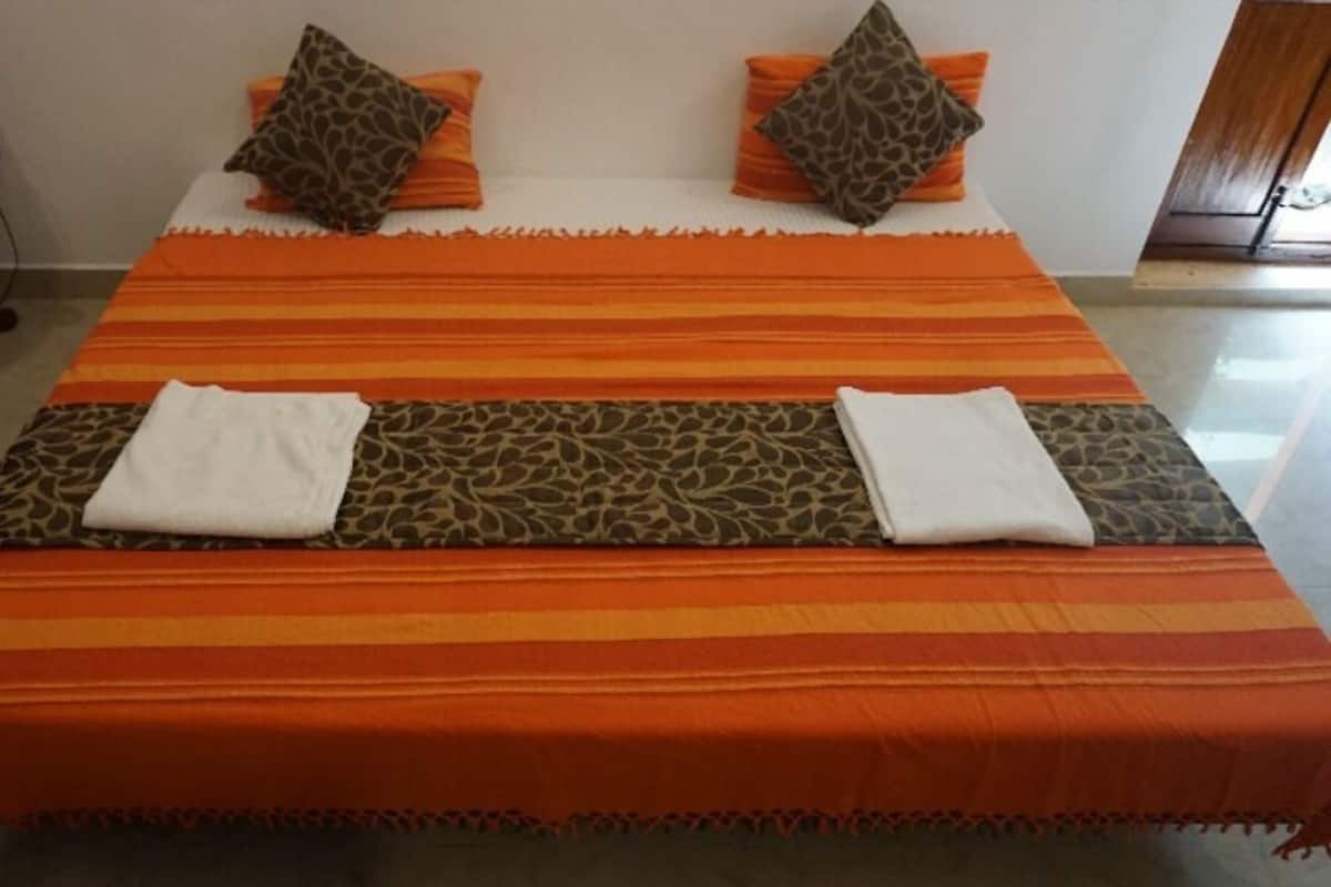 A bed with a striped orange and brown bedspread, two pillows, and two folded white towels.