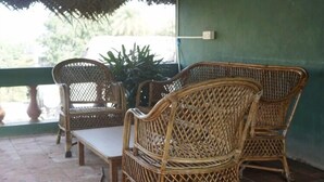 Mueble de mimbre con asiento y respaldo acolchados, sobre un suelo de baldosas.