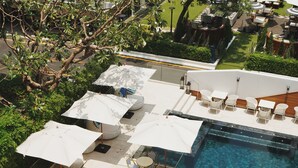 Un área de piscina en la azotea con sillones, sombrillas y una vista despejada de la piscina.