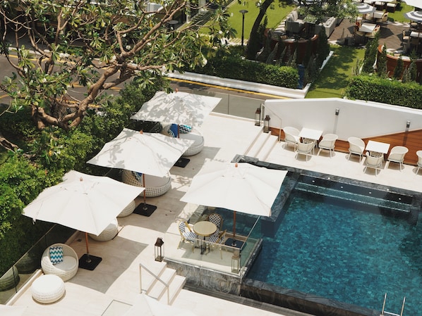 Uma área de piscina no terraço com espreguiçadeiras, guarda-sóis e vista desobstruída da piscina.
