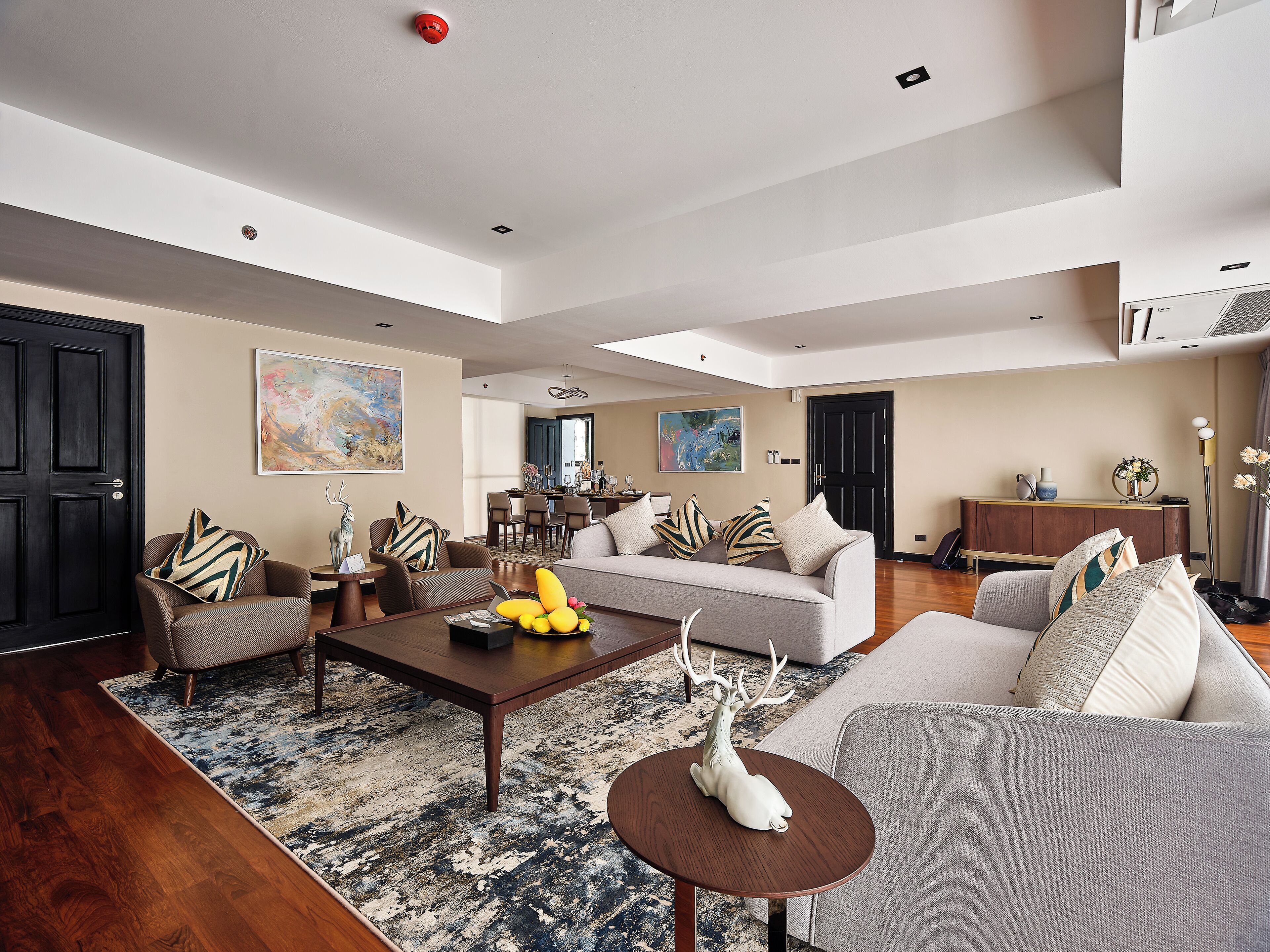 A spacious living room with a large sofa, a coffee table, and a dining area in the background.