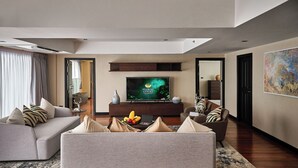 Una sala de estar moderna con un sofá gris, una mesa de centro con fruta y un televisor de pantalla plana sobre un soporte de madera.