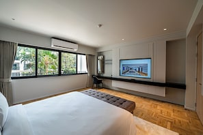 A modern hotel room with a large bed, a TV mounted on the wall, and a view of the outdoors. - Floral Court Hotel & Residence Sukhumvit 13 (Bangkok)