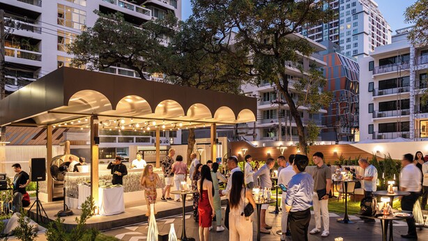 Un espacio para eventos al aire libre con mesas y sillas, rodeado de edificios.