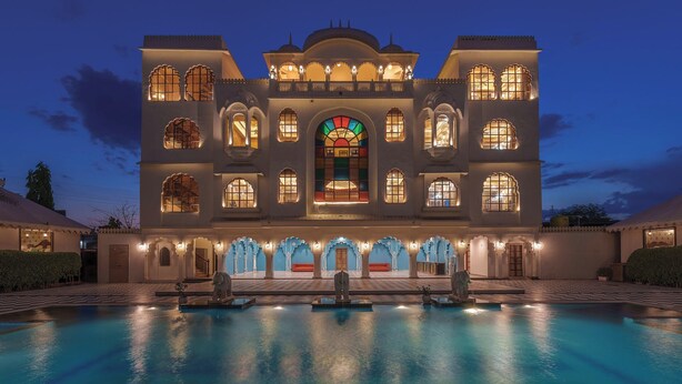 A large, multi-story building with a swimming pool in front. - R Chandras Palace  (Chomu)