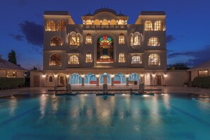 A large, multi-story building with a swimming pool in front.