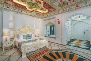 A luxurious bedroom with an ornate bed, a large mirror, and a patterned floor.