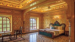 A room with a large bed, ornate wooden paneling, and a patterned floor. - R Chandras Palace  (Chomu)