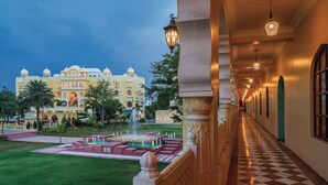 A hotel corridor with a checkered floor, a fountain, and a large building with domes in the background. - R Chandras Palace  (Chomu)