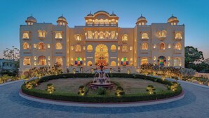A large, ornate building with multiple windows and a central entrance, surrounded by a well-manicured garden and a fountain. - R Chandras Palace  (Chomu)