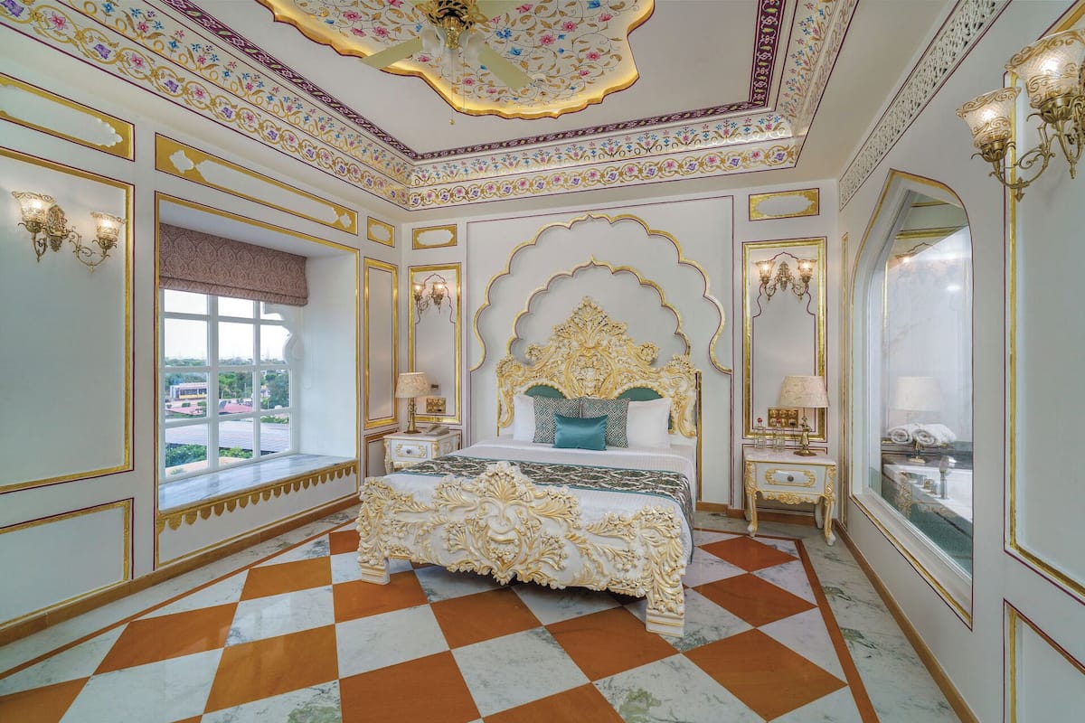 A luxurious bedroom with a large bed, ornate ceiling, and a checkered floor.