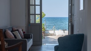Uma sala de estar moderna com vista para o mar através de uma porta aberta.