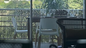 A balcony with a table set for dining, chairs, and a view of a green landscape. - Cosy  Apt on friar’s bay SxM . 2 min to the Friar’s Bay beach ,restaurants (Saint Martin)