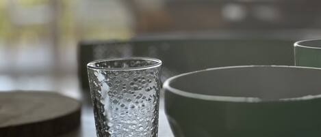 Et glas med et struktureret mønster og en grøn skål på et bord.
