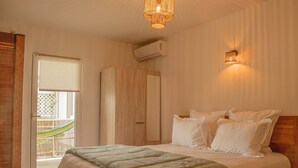A bedroom with a bed, a wardrobe, a window with a view, and a wall-mounted air conditioner. - Cosy  Apt on friar’s bay SxM . 2 min to the Friar’s Bay beach ,restaurants (Saint Martin)