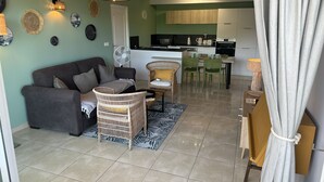 A living room with a sofa, wicker chairs, a coffee table, and a dining area with chairs and a table. - Cosy  Apt on friar’s bay SxM . 2 min to the Friar’s Bay beach ,restaurants (Saint Martin)