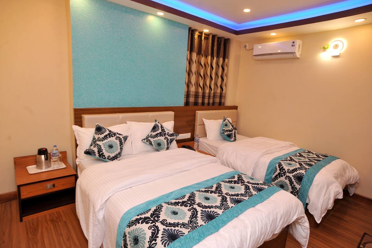 A hotel room with two beds, a nightstand, a wall-mounted air conditioner, and a decorative light fixture.