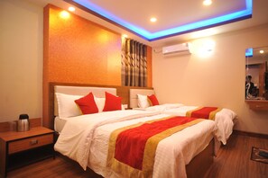 A hotel room with a large bed, a nightstand, and a wall-mounted air conditioner. - Hotel Aarati (Kathmandu)