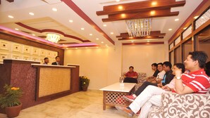 A reception area with a reception desk, seating, and a chandelier. - Hotel Aarati (Kathmandu)
