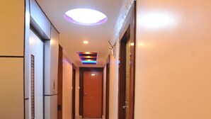 A hotel hallway with a carpeted floor, a wooden door at the end, and a ceiling light fixture. - Hotel Aarati (Kathmandu)