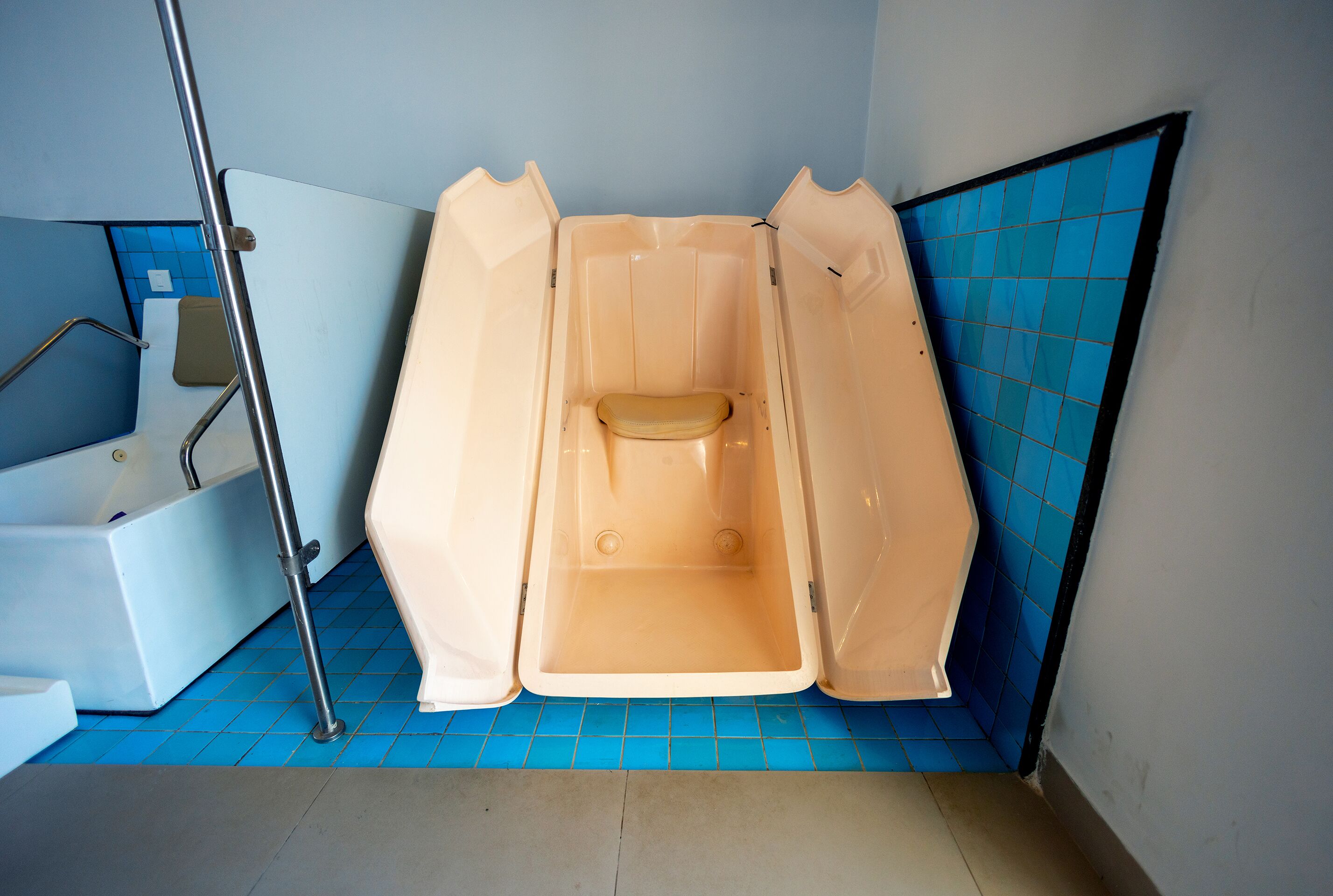 Et lille badeværelse med badekar, toilet og bruseniche.