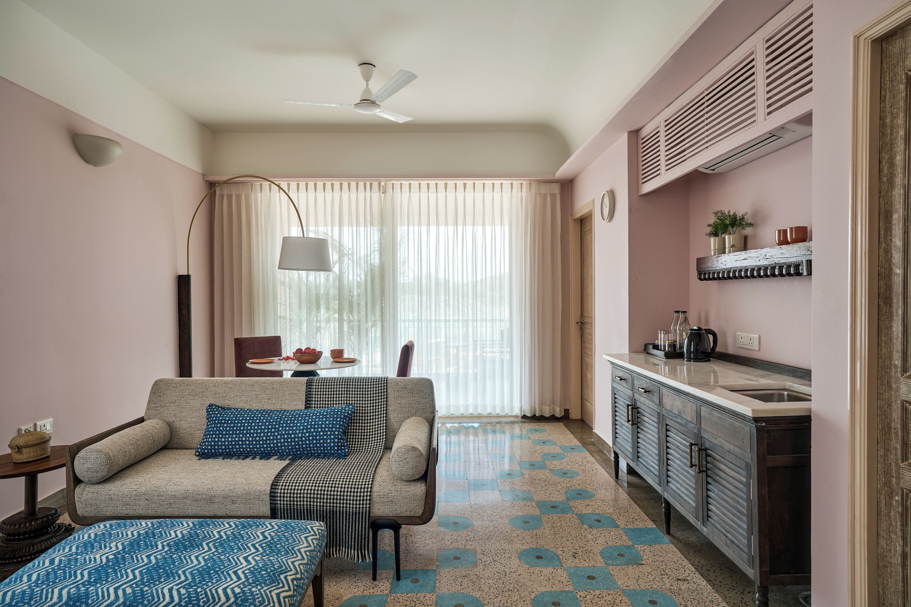 A living room with a sofa, a dining table, and a kitchen area with a sink and cabinets.
