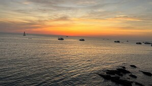 Tyyni meri auringonlaskun aikaan, näkyvissä veneitä ja purjevene.