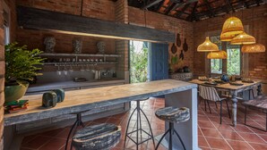 Uma cozinha rústica com paredes de tijolos aparentes, balcão de madeira e luminárias de vime suspensas.