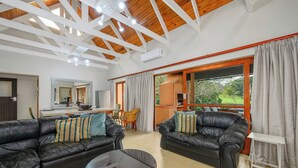 A spacious living area with two black leather sofas, a glass coffee table, and a dining area with a wooden table and chairs. - San Lameer Villa 2704 (Southbroom)