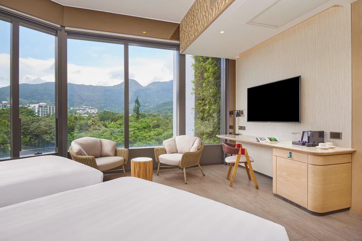 Ein Hotelzimmer mit zwei Betten, einem Fernseher, einem Schreibtisch, Korbsesseln und Bergblick.