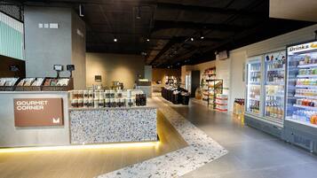 A grocery store interior with a 'Gourmet Corner' section, refrigerated drink cases, and a variety of packaged goods.