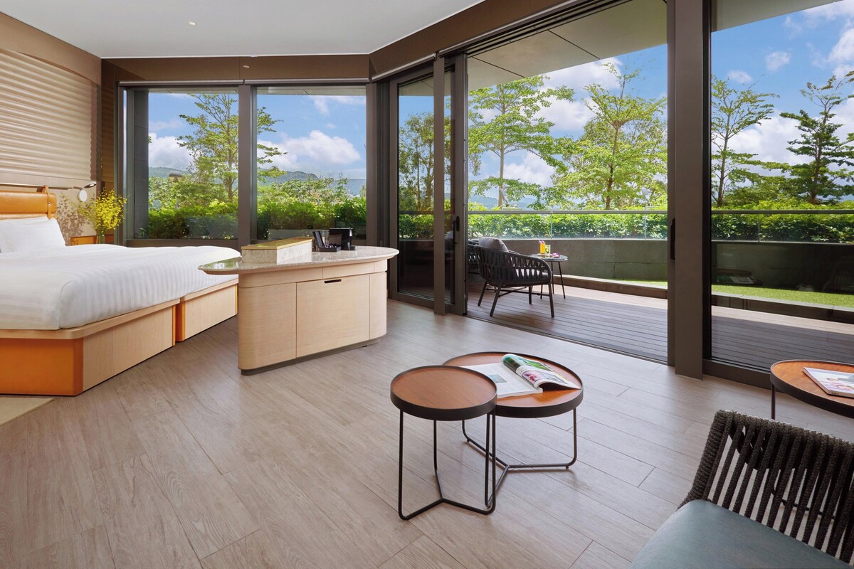 Une chambre moderne dotée d’un grand lit, d’un petit coin cuisine et d’un balcon avec un espace salon extérieur.